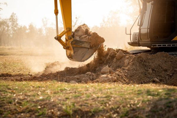 Backhoe working by digging soil at construction site. Crawler excavator digging on demolition site.